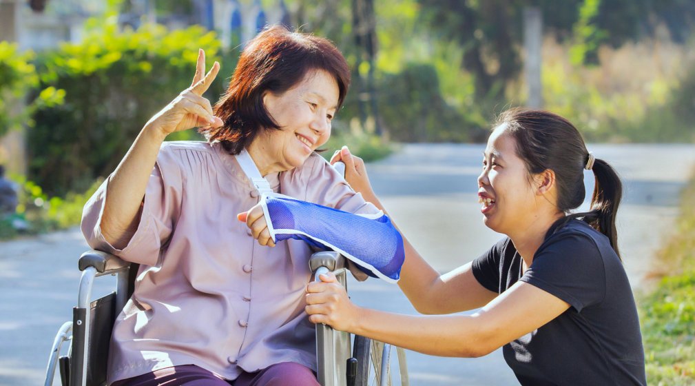 smiling disabled old woman in a wheelchair assisted by her caregiver